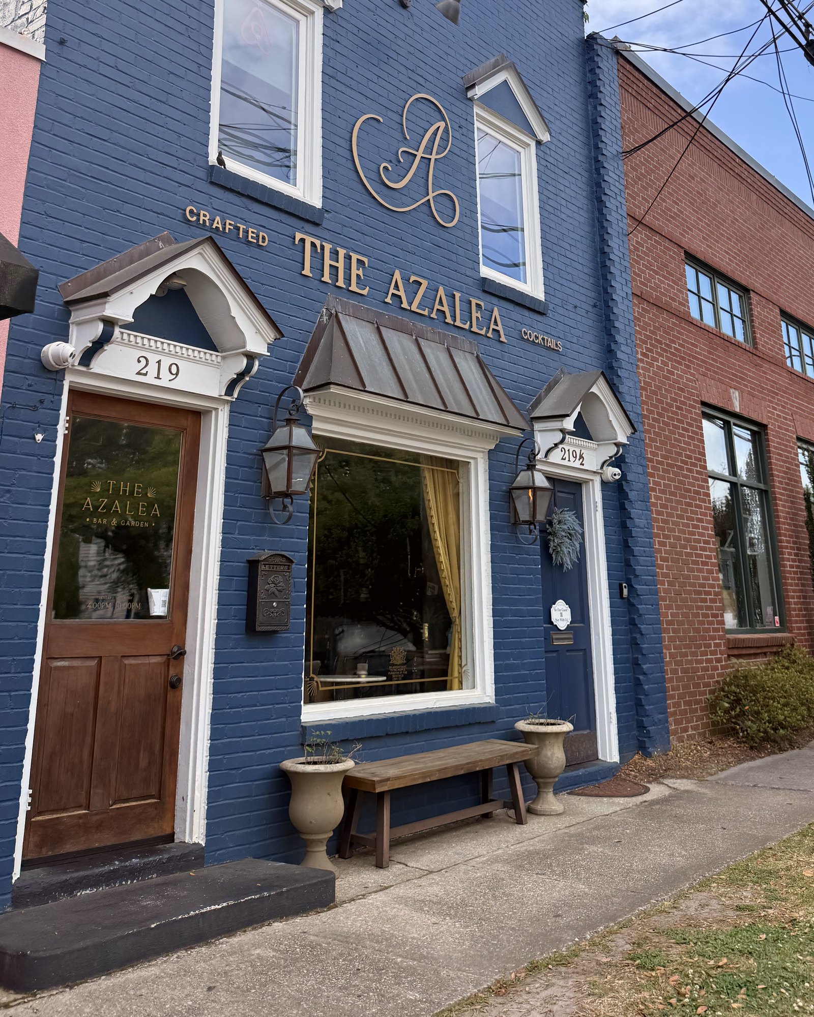 The blue-painted brick storefront of The Azalea Bar and Garden in downtown Summerville