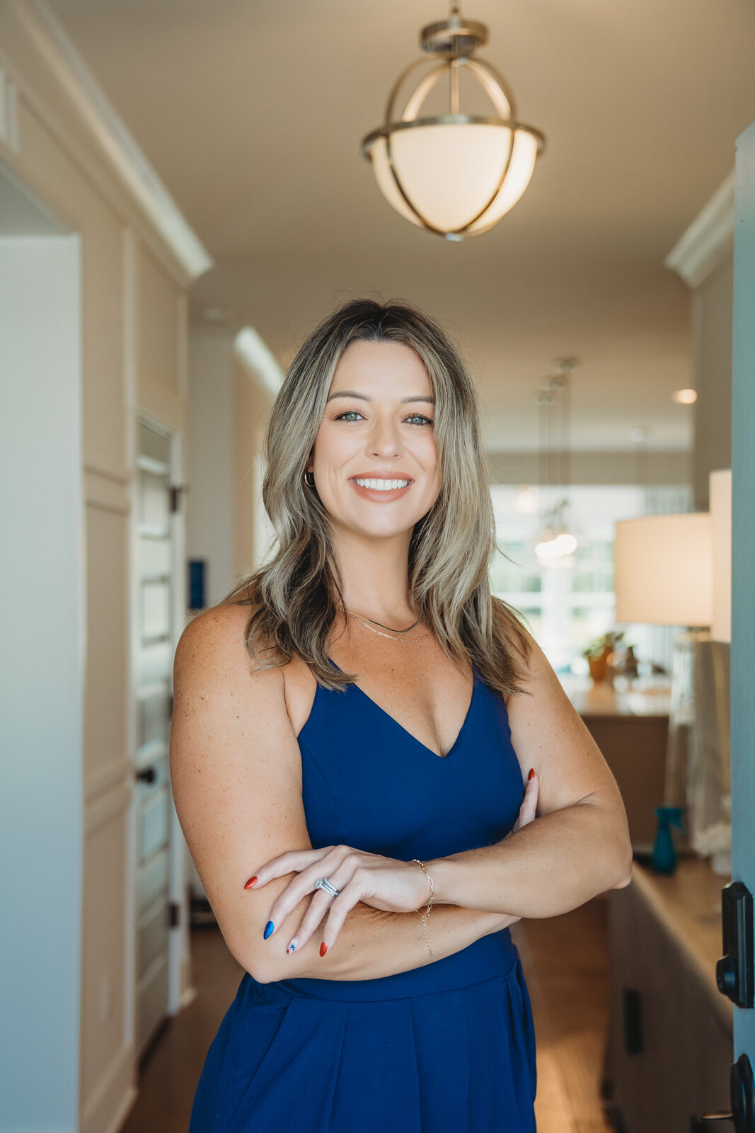 Megan Duncan standing in a bright hallway with her arms crossed, smiling