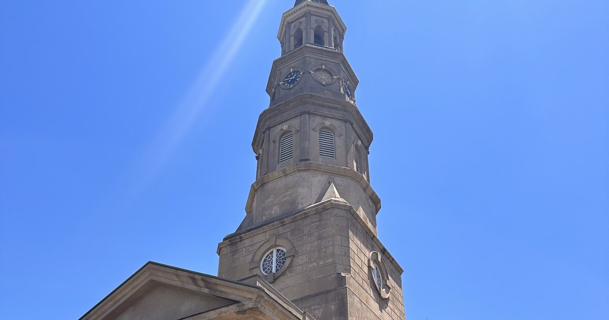 Steeple and columned portico of St. Philip's Church against a blue sky on Church Street in Charleston