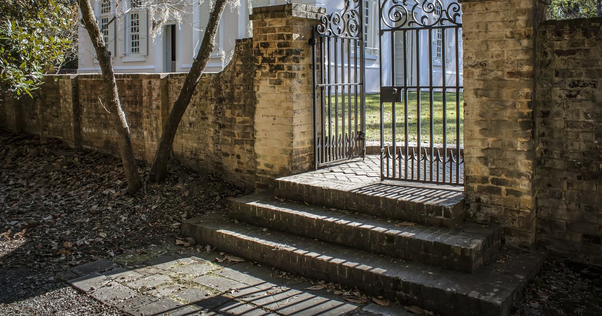 Brick steps and the wrought-iron gate of the 1719 St. James Goose Creek parish church under live oak shade