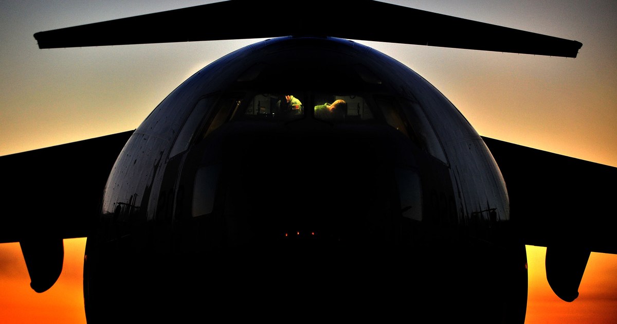 A C-17 Globemaster III silhouetted head-on against an orange dusk sky at Joint Base Charleston