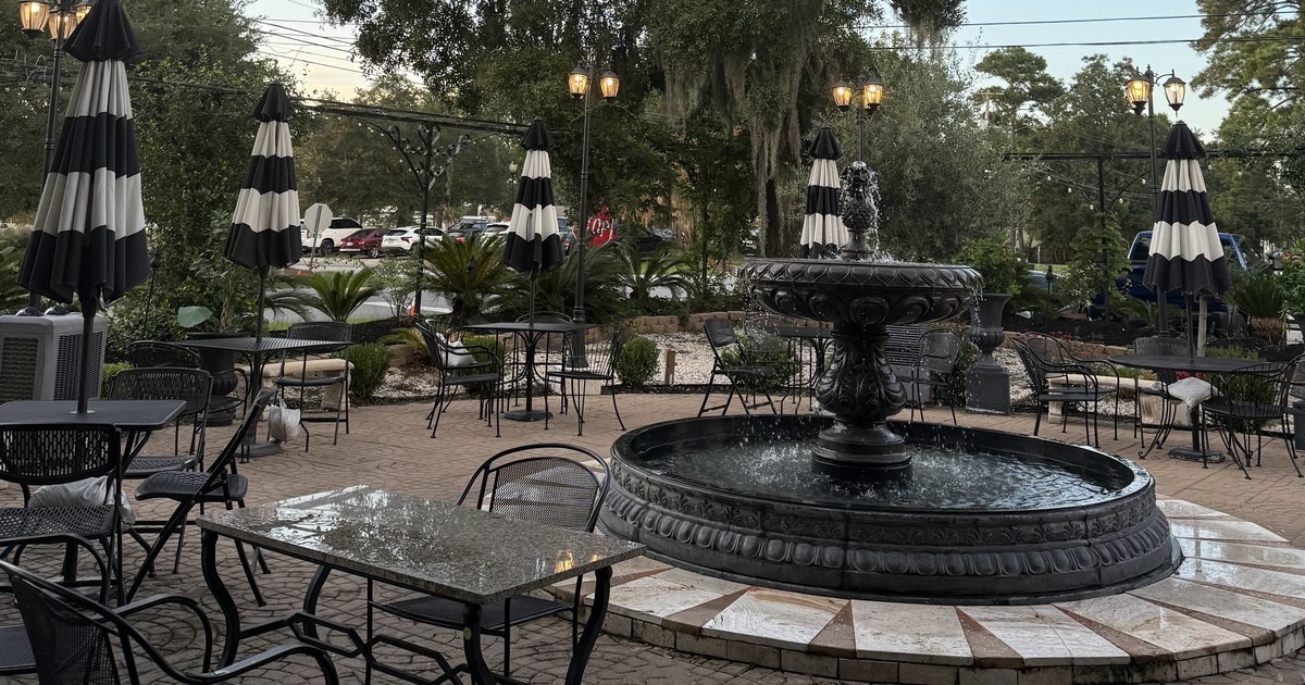 Cast-iron fountain and striped cafe umbrellas under a live oak at dusk on the Short Central plaza in downtown Summerville